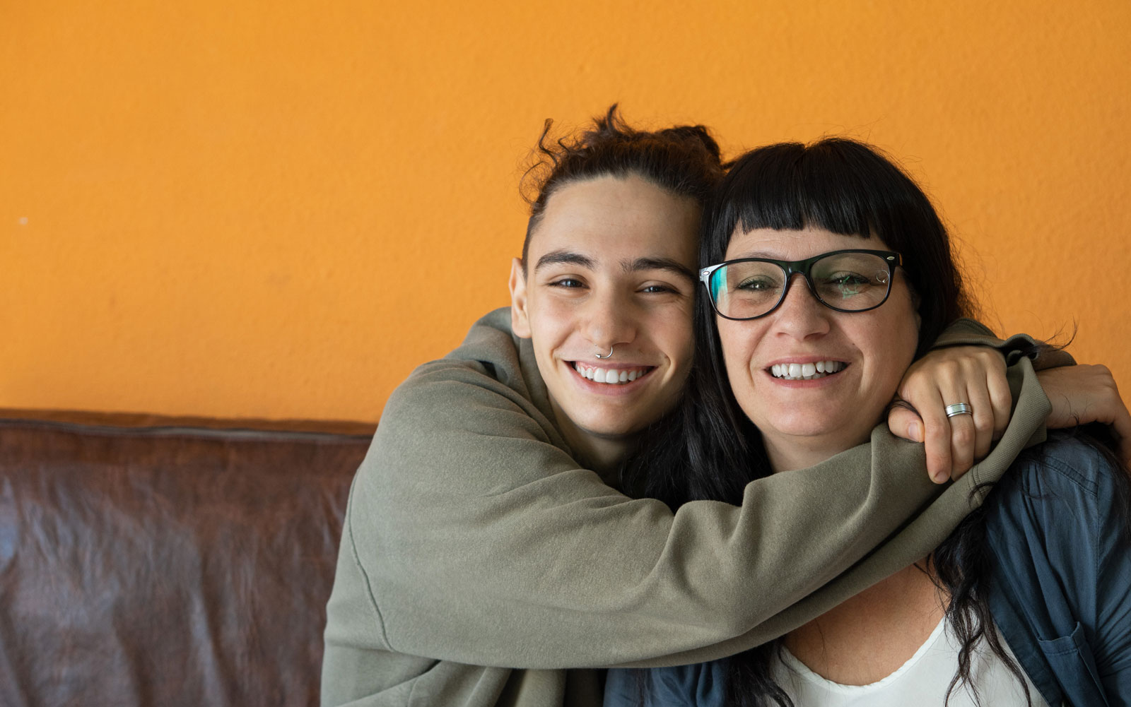 Teenager having a big hug with woman wearing glasses